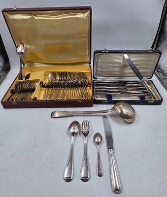 des couverts rangés dans un coffret posé sur une table, à côté d'autres couverts