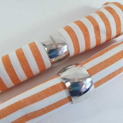 orange and white striped napkins with silver napkin rings on them