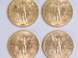 four gold coins of different sizes and shapes on a white surface