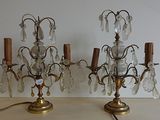 une paire de chandeliers anciens en laiton et cristal posés sur une table en bois
