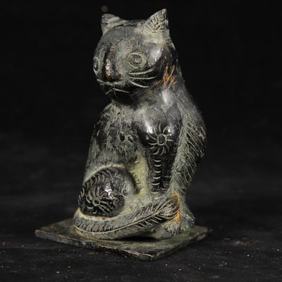 statue of a cat holding a fish in its paws on a black background