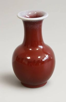 un vase rouge bordé de blanc posé sur une table
