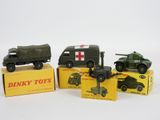 Trois véhicules militaires miniatures sont posés sur des cartons, sur une surface blanche.
