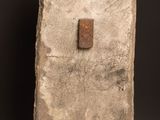 an old stone block with a rusted metal button on a wooden table