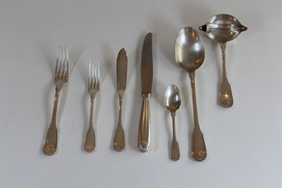 a lot of silver spoons and forks laid out on a table