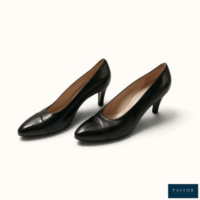Les chaussures noires de la femme reposent sur une surface blanche.