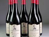 trois bouteilles de vin rouge posées sur une table l'une à côté de l'autre
