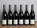 six bouteilles de vin sont alignées sur une table en bois