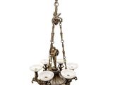 a brass chandelier with five white glass shades hanging from the ceiling