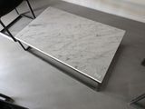une table en marbre blanc avec une chaise noire en arrière-plan