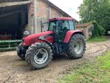 un tracteur rouge garé devant une grange