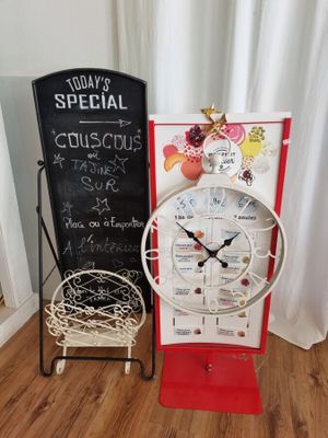 une horloge posée sur un pied à côté d'un tableau noir