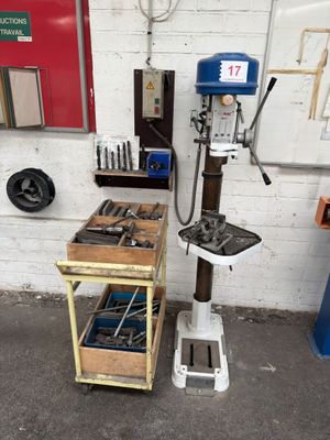 a drill press in a workshop with tools on the table