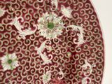 a red plate with white and green designs on it