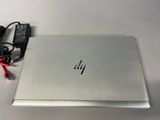 hp laptop with power cord and charger sitting on a table