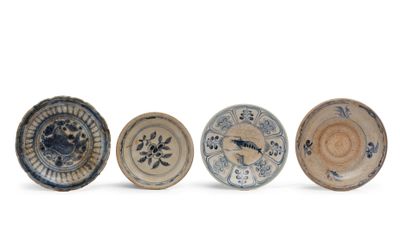 quatre petites assiettes bleues et blanches ornées de motifs, posées sur un fond blanc