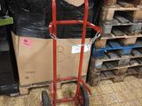 a red hand truck that is next to a pile of boxes