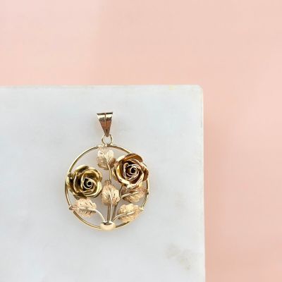 yellow gold rose pendant on a white marble block