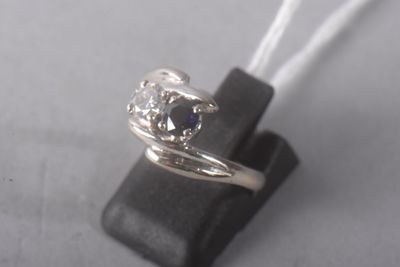 a silver ring with a blue diamond on it on a black piece of leather