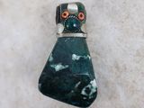 a close up of a green stone with an orange eye on it