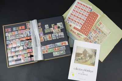 un livre ouvert sur lequel figurent des timbres et un livret avec la photo d'un bâtiment