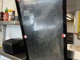 a man that is standing in a kitchen with a blackboard