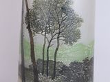 a glass vase with a picture of trees on it