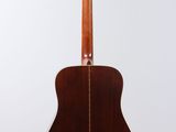 an acoustic guitar hanging from the back of a white wall