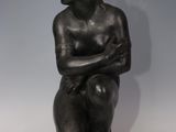 a bronze statue of a woman sitting on a rock