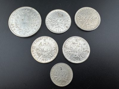 six types différents de pièces d'argent sur une surface noire