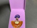 perfume bottle in a purple box on a table next to a glass of wine