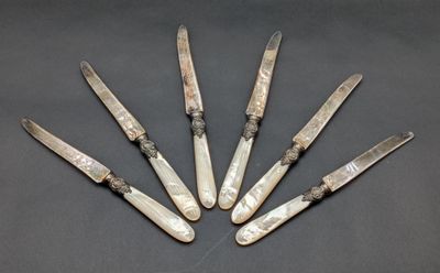 six knives are lined up in a circle on a table