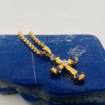 une croix en or posée sur une pierre bleue, accompagnée d'une chaîne