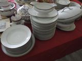 many plates and bowls on a table with a red table cloth