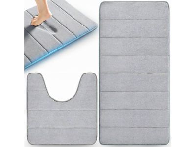 une personne debout sur une serpillière et un tapis de bain