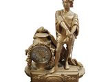 une statue en or représentant un homme avec une horloge posée sur une table