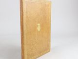 an old book with a golden cover sitting on a white surface