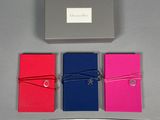 quatre cahiers de couleurs différentes attachés à une boîte posée sur une table