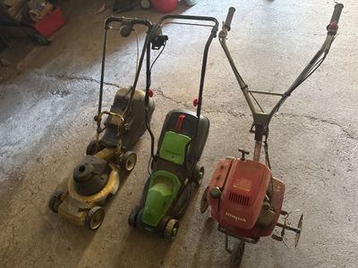Plusieurs tondeuses à gazon sont alignées sur le sol d'un garage