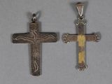 deux pendentifs en forme de croix, en argent et en or, sur un fond gris