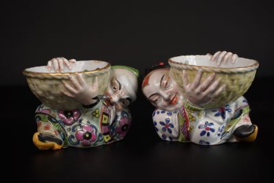 deux figurines représentant un homme et une femme avec des bols sur la tête
