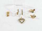 trois paires de boucles d'oreilles et une broche posées sur un fond blanc