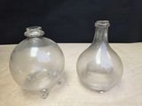two glass vases sitting on a table next to each other