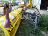 a yellow snow plow sitting in the grass