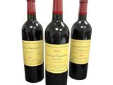 trois bouteilles de vin rouge posées l'une à côté de l'autre sur une surface blanche