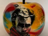 une image représentant une pomme peinte sur laquelle figure le portrait d'un homme