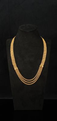 un collier à chaîne en or sur un mannequin, sur fond noir