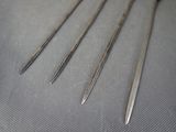 four pairs of surgical needles are sitting on a table