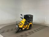 une moto garée dans une pièce, avec un carton à l'arrière