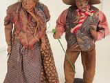 pair of antique dolls of a man and a woman with hats and scarves